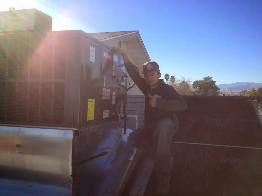 HVAC technician performing Air Duct Cleaning on a rooftop unit in Landover